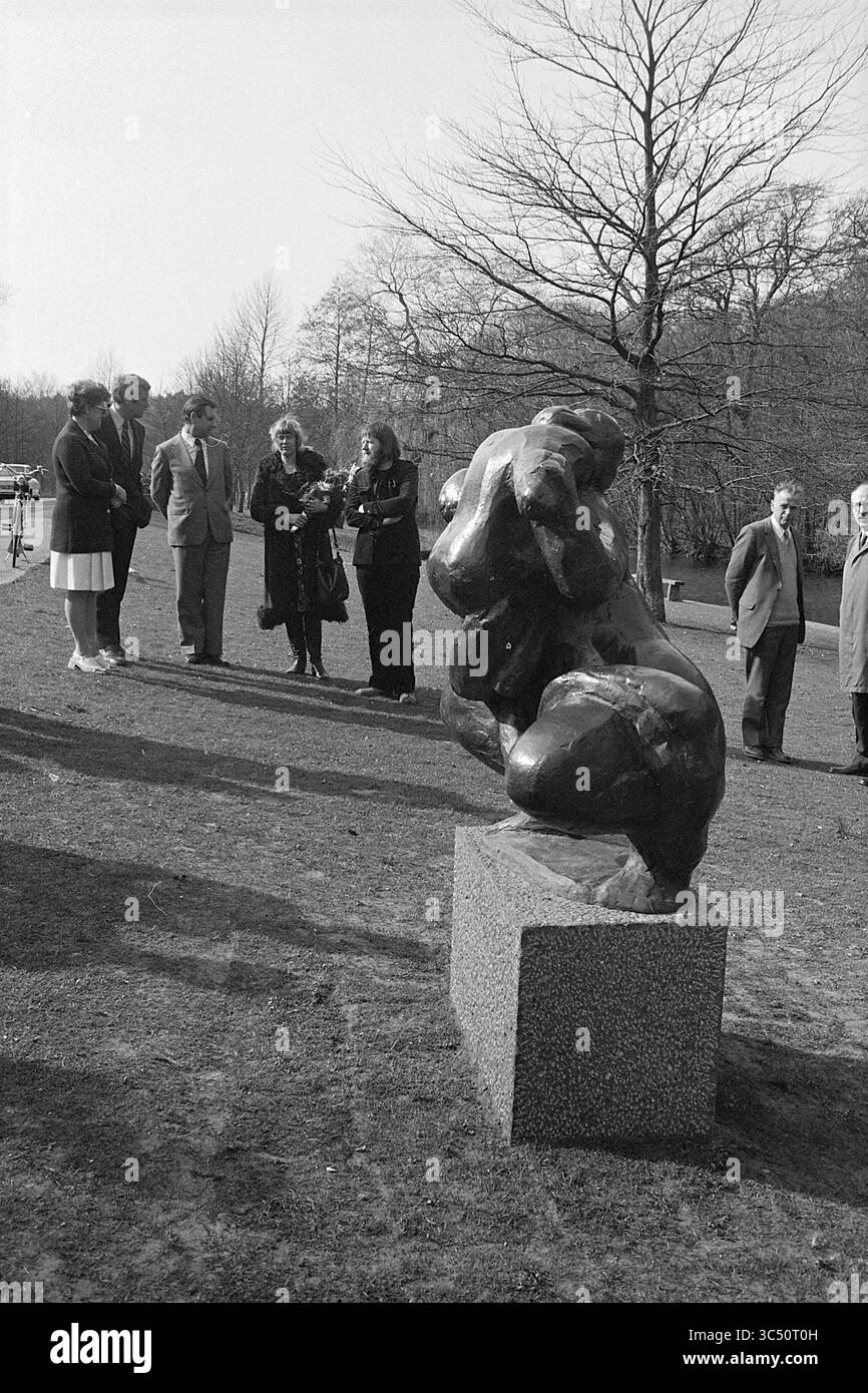 Presentazione della scultura "donna con bambino" di NIC Jonk, Overveen, Duinlustweg Whizgle News, Dutch Desk, Paesi Bassi, 1950-2000 Un gruppo di persone si riunisce intorno a una scultura impressionante, impegnandosi in discussioni e apprezzandone la forma artistica. L'ambiente presenta un paesaggio naturale con alberi sullo sfondo, che aggiunge un'atmosfera tranquilla. Foto Stock