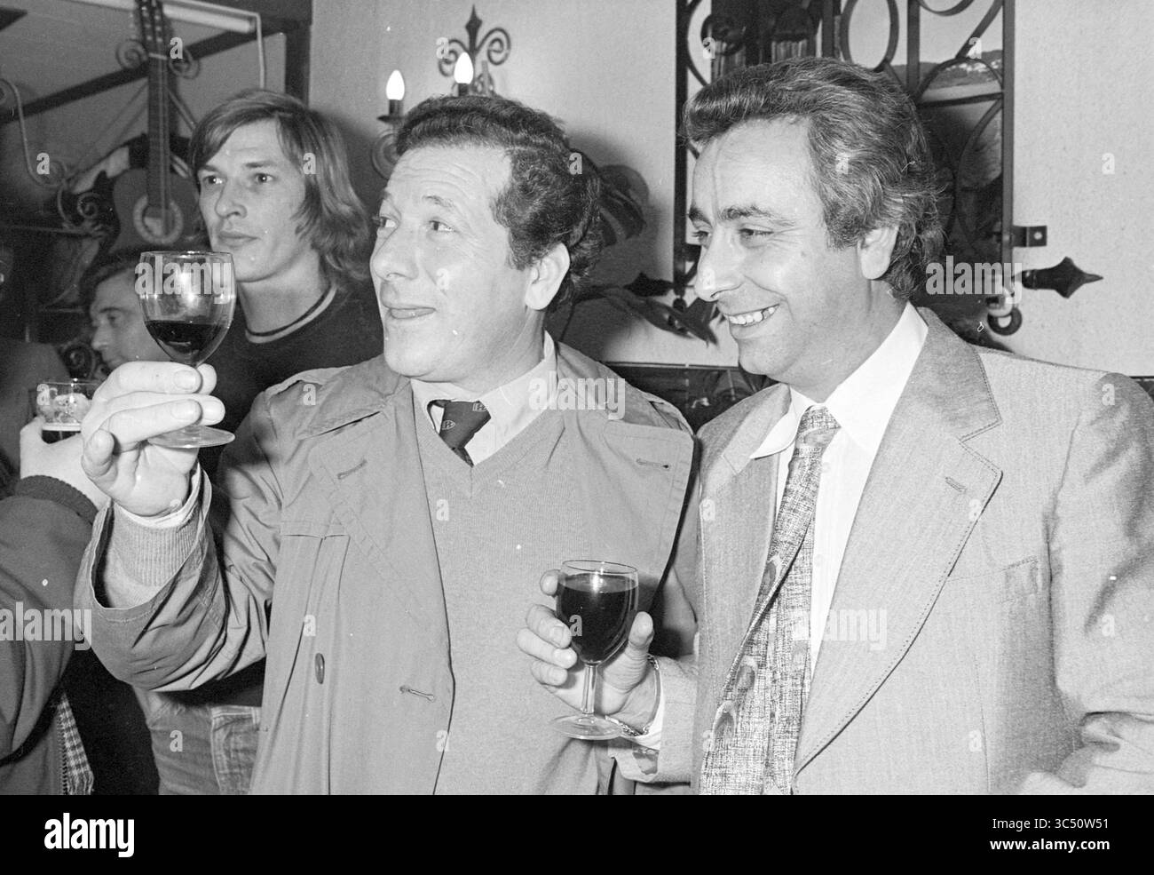 Apertura del ristorante [la] Quimera, apertura, apertura, ristorante, 08-11-1978 Whizgle News, Dutch Desk, Paesi Bassi, 1950-2000 due uomini alzano i bicchieri in un brindisi celebrativo, sorridono sui loro volti, circondati da un vivace raduno in un ambiente accogliente decorato con strumenti musicali e luci calde. Foto Stock