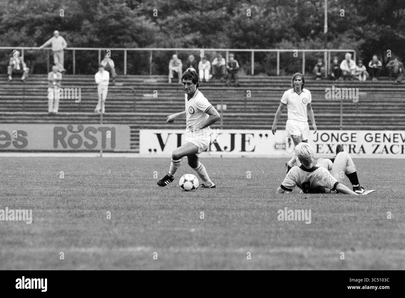 Action Douglas George Telstar, Football Telstar, 31-07-1981 Whizgle News, Dutch Desk, Paesi Bassi, 1950-2000 Una partita di calcio in azione, che mette in mostra due giocatori sul campo: uno dribbling sapientemente la palla mentre l'altro è a terra, caduto durante il gioco. Gli spettatori possono essere visti in sottofondo, osservando l'atmosfera competitiva. Foto Stock