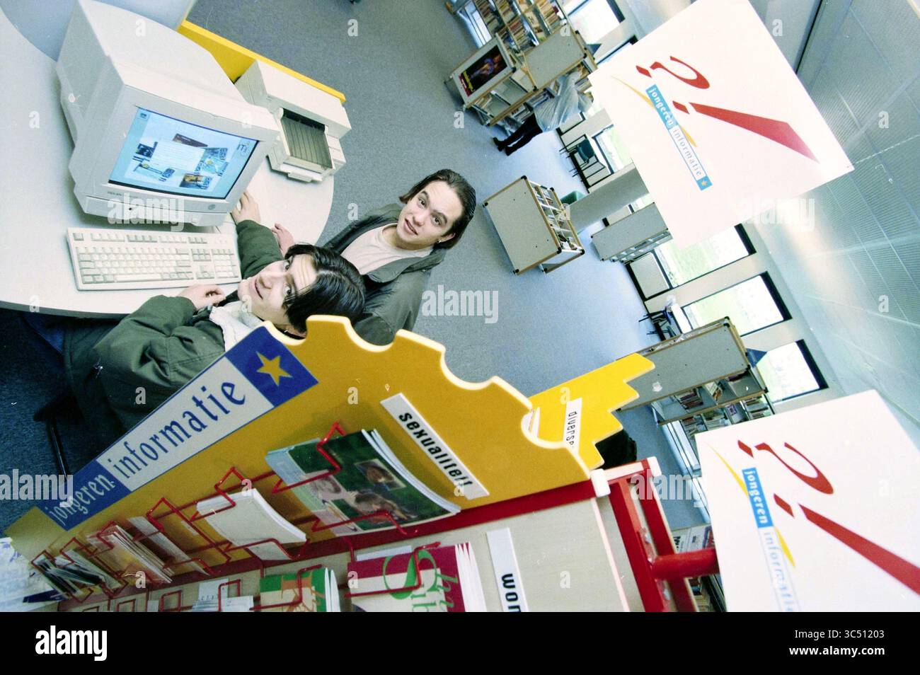 Punto di informazione per i giovani. Velserbroek Library, Velserbroek, 10-03-1998 Whizgle News, Dutch Desk, Paesi Bassi, 1950-2000 due persone sono coinvolte in un computer in uno spazio di lavoro moderno pieno di espositori informativi e scaffali. La segnaletica luminosa mette in risalto vari argomenti, mentre un'atmosfera invitante incoraggia l'esplorazione e l'apprendimento. Foto Stock