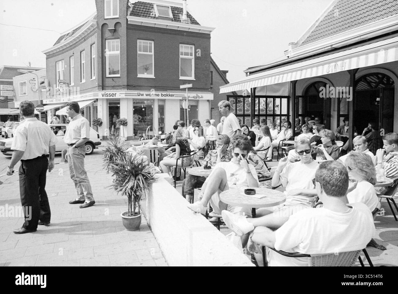Spiaggia - villaggio - atmosfera, Z'voort, Zandvoort, 24-07-1992 Whizgle News, Dutch Desk, i Paesi Bassi, 1950-2000 Una vivace scena di caffè all'aperto piena di persone che si divertono la giornata. I gruppi sono seduti ai tavoli, alcuni impegnati in una conversazione, mentre altri si rilassano con un drink. Nelle vicinanze si trovano alcuni individui, che contribuiscono all'atmosfera vivace, in mezzo a uno sfondo di negozi accoglienti e clima soleggiato. Foto Stock