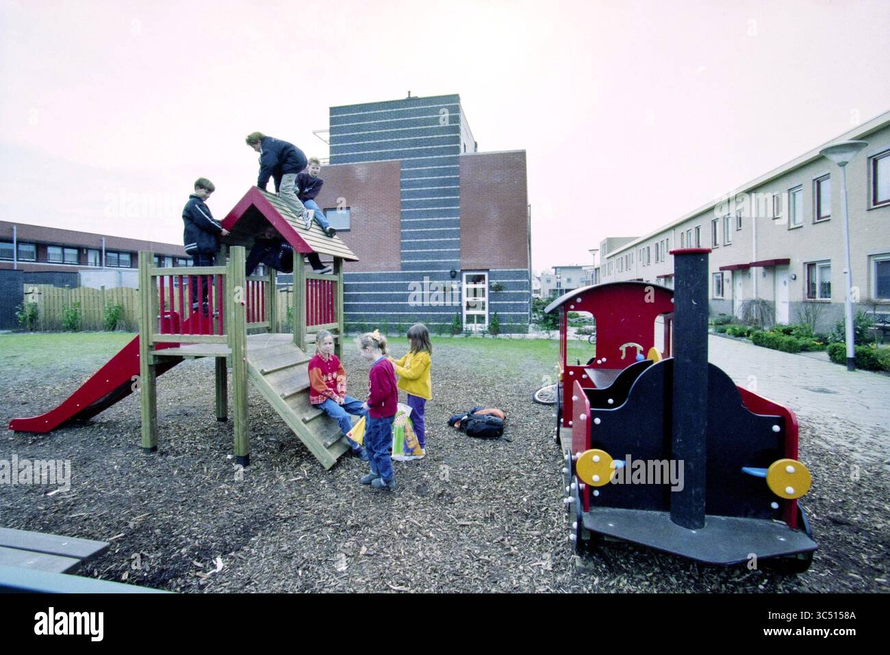 Premio informatico alla scuola Wadden, Haarlem, Paesi Bassi, 24-03-1999 Whizgle News, Dutch Desk, i Paesi Bassi, 1950-2000 Un gruppo di bambini gioca in un parco giochi colorato, con un bambino che si arrampica in cima a una struttura di gioco. Altri sono riuniti intorno a un trampolino e uno scivolo, impegnandosi in varie attività mentre si divertono nell'ambiente esterno. Gli edifici vicini fanno da sfondo alla loro scena giocosa. Foto Stock
