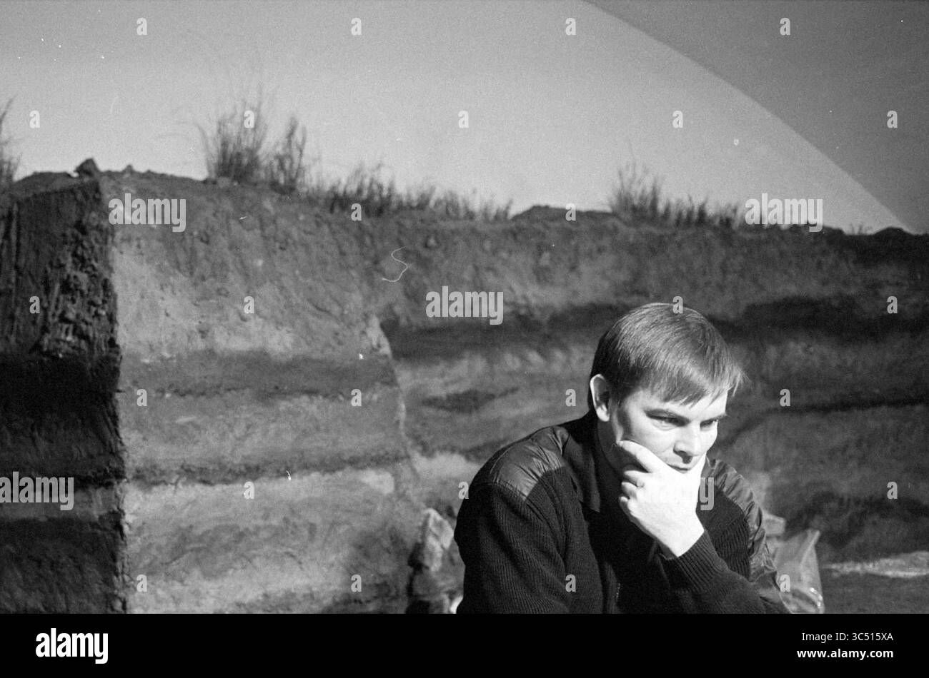 Maarten Polderman, archeologo, Haarlem, Paesi Bassi, 15-11-1992 Whizgle News, Dutch Desk, Paesi Bassi, 1950-2000 Una figura contemplativa siede davanti a uno sfondo di terra testurizzata, perso nel pensiero, con ciuffi di erba che sbirciano sopra gli strati del suolo. Foto Stock