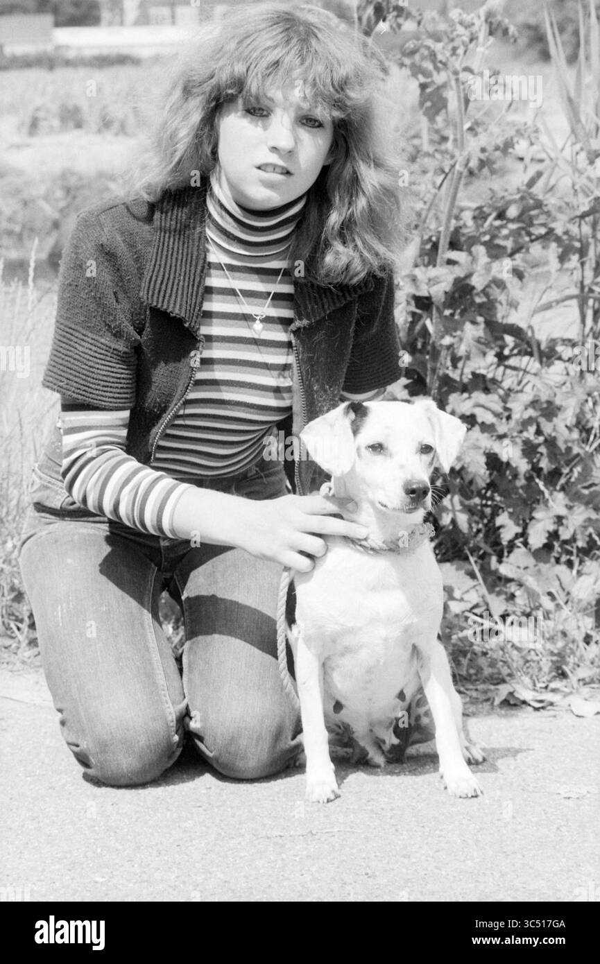 Dog v.d. WEEK, Dogs, 19-07-1978 Whizgle News, Dutch Desk, Paesi Bassi, 1950-2000 Una giovane donna con i capelli ondulati si inginocchia accanto a un piccolo cane, entrambi guardano direttamente allo spettatore. È vestita con un dolcevita a righe e un giubbotto, mentre il cane si siede con attenzione, mostrando il suo comportamento giocoso su uno sfondo naturale. Foto Stock Dog v.d. WEEK, Dogs, 19-07-1978 Whizgle News, Dutch Desk, Paesi Bassi, 1950-2000 Una giovane donna con i capelli ondulati si inginocchia accanto a un piccolo cane, entrambi guardano direttamente allo spettatore. È vestita con un dolcevita a righe e un giubbotto, mentre il cane si siede con attenzione, mostrando il suo comportamento giocoso su uno sfondo naturale. Foto Stock