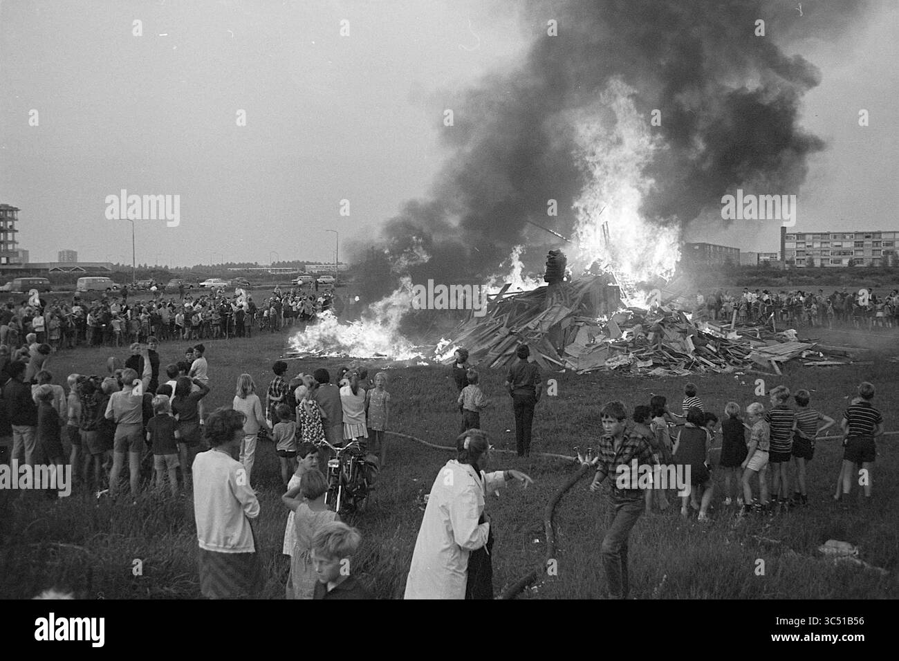 Capanne bruciate a Schalkwijk, giochi per le vacanze, giorni festivi, campo vacanze, 09-08-1968 Whizgle News, Dutch Desk, Paesi Bassi, 1950-2000 Una grande folla si raduna vicino a un enorme falò che emana fumo mentre le fiamme consumano un mucchio di detriti. Persone di tutte le età guardano con attenzione, alcuni scattano fotografie, mentre altri stanno con le mani in tasca, creando una scena piena di curiosità ed eccitazione. Foto Stock