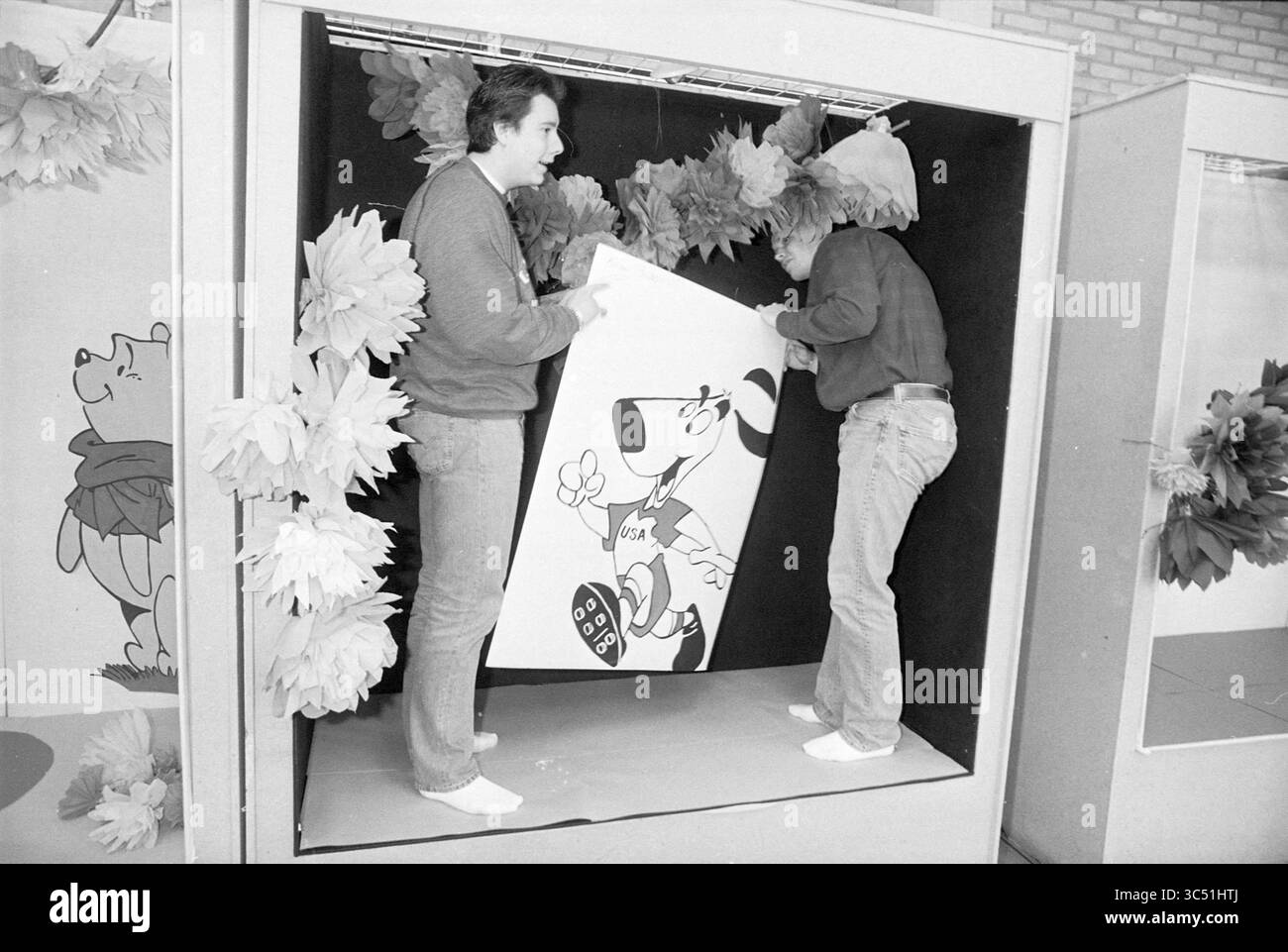 Corso di vetrina, Schalkwijk, Haarlem, Paesi Bassi, 08-03-1994 Whizgle News, Dutch Desk, Paesi Bassi, 1950-2000 due persone sono impegnate a organizzare un grande spettacolo a tema cartoni animati con un personaggio di cane. Sono circondate da colorate decorazioni floreali, che aggiungono un'atmosfera festosa alla scena. Foto Stock