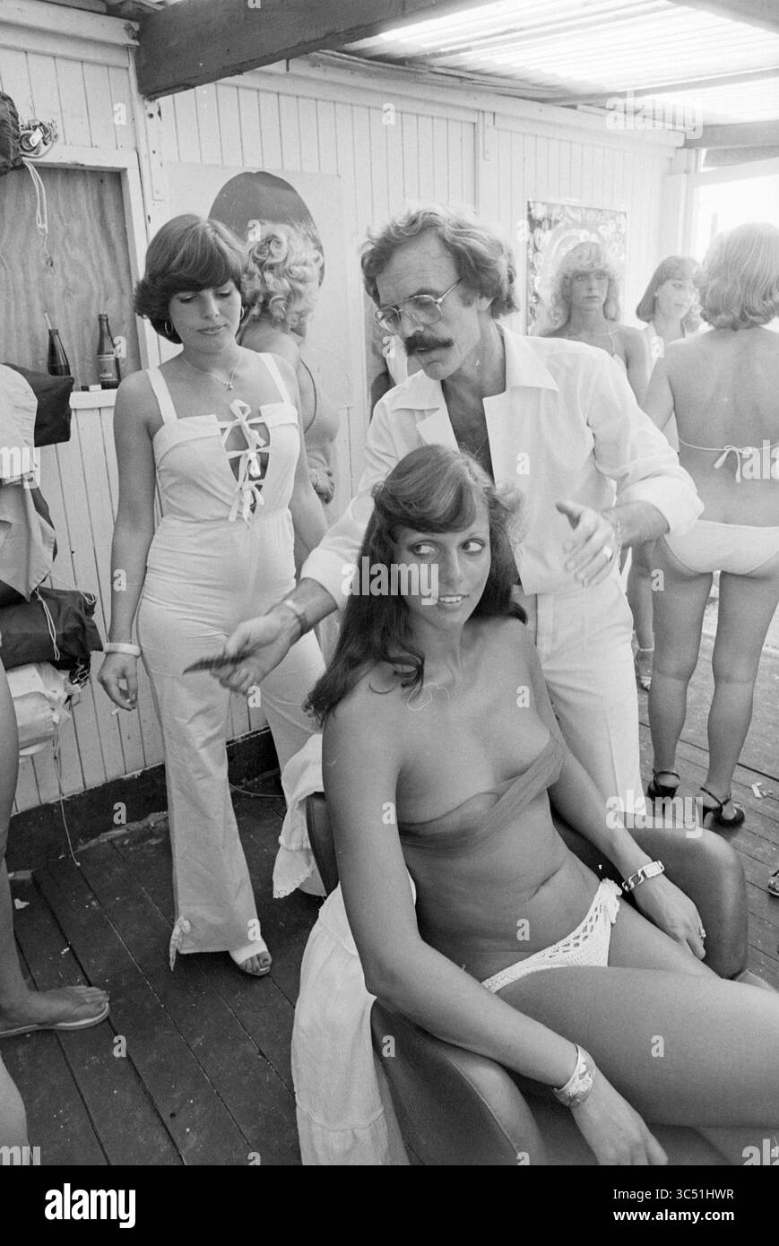 Miss Beach Election Zandvoort, Miss Election, 19-08-1978 Whizgle News, Dutch Desk, Paesi Bassi, 1950-2000 in un vivace salone, un parrucchiere cura sapientemente i capelli di una modella seduta, mentre un'altra modella osserva nelle vicinanze, entrambi mostrando moda anni '1970 e acconciature. L'atmosfera è vibrante e vivace, piena di energia di una sessione di trasformazione creativa. Foto Stock