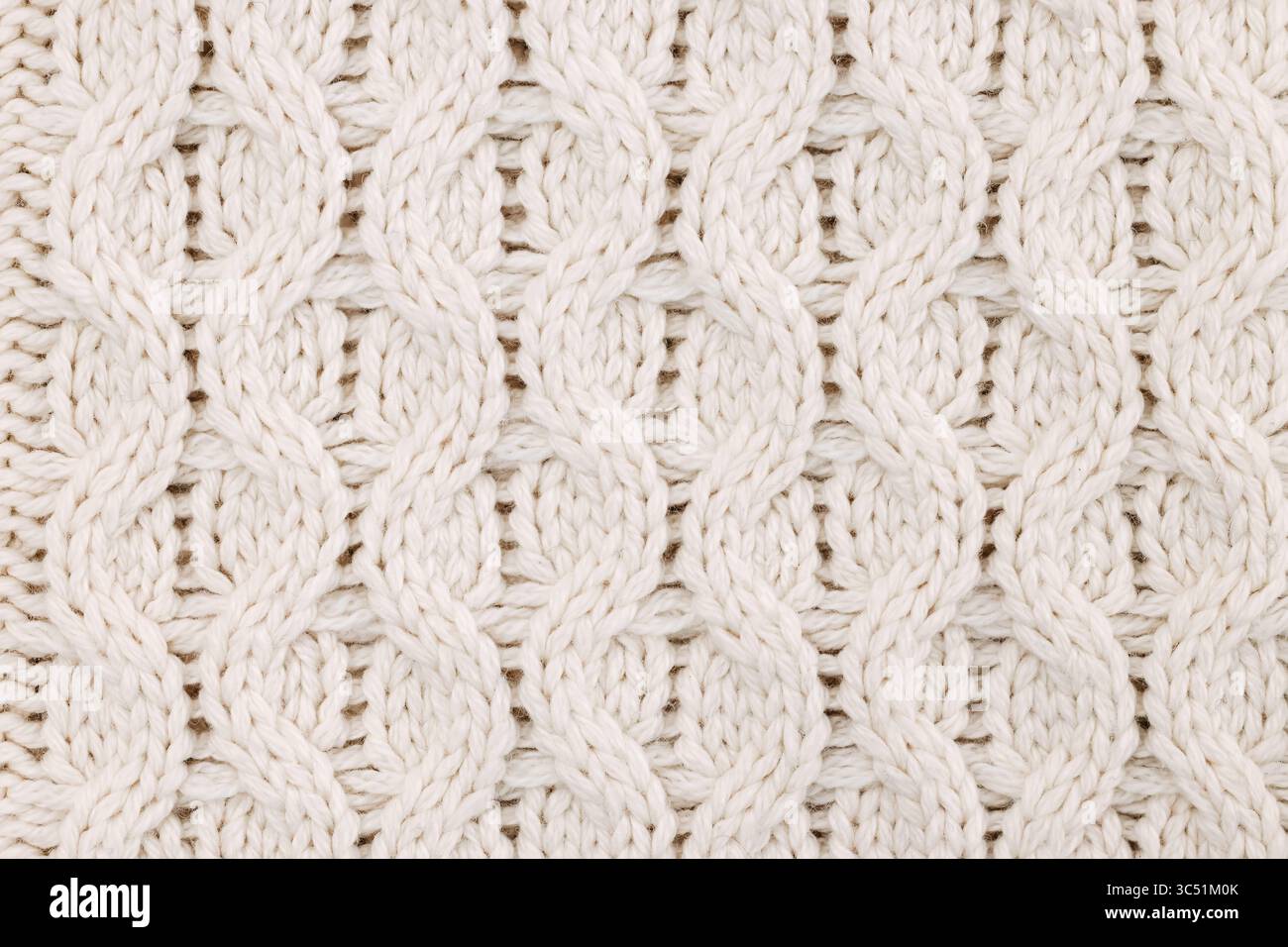 Un'immagine dettagliata di un motivo a maglia bianca che mette in risalto l'intricata trama del tessuto. Foto Stock