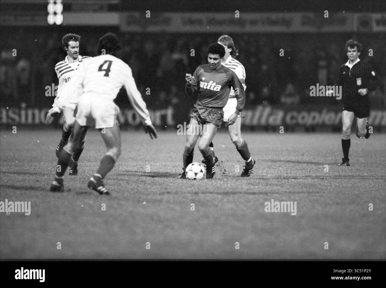 Haarlem - FC Den Bosch, Football Haarlem, 02-02-1985 Whizgle News, Dutch Desk, Paesi Bassi, 1950-2000 Una dinamica scena di calcio in cui i giocatori sono in azione, con un atleta che manovra abilmente la palla mentre è circondato dagli avversari, mostrando l'intensità del gioco. Un arbitro osserva da vicino il gioco sullo sfondo. Foto Stock