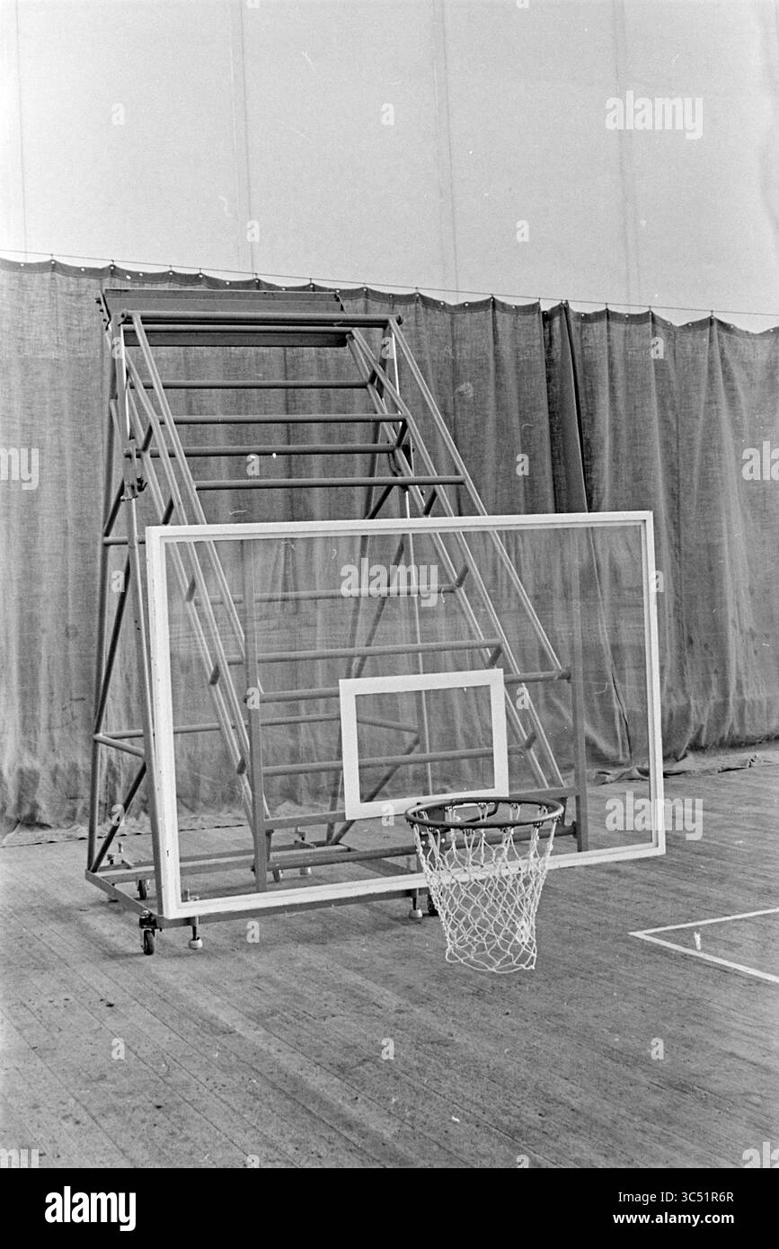 Basketball NET, 00-01-1966 Whizgle News, Dutch Desk, Paesi Bassi, 1950-2000 Un canestro da basket e disposizione del backboard posizionati su un campo, con una grande struttura pieghevole sullo sfondo, che indica un ambiente di allenamento o di pratica. Foto Stock