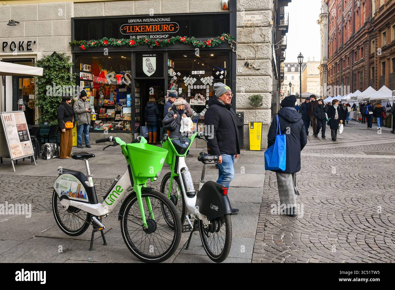 Biciclette elettriche parcheggiate di fronte alla storica libreria lussemburghese, con bancarelle in via Cesare Battisti in inverno, Torino, Piemonte, Italia Foto Stock