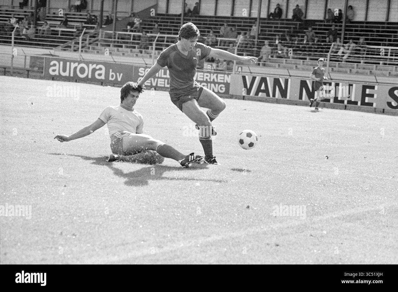 Partita di calcio HFC Haarlem, 22-09-1979 Whizgle News, Dutch Desk, Paesi Bassi, 1950-2000 due giocatori di calcio si impegnano in un gioco impegnativo sul campo. Un giocatore tenta di far scivolare l'altro, che riesce ad allontanare abilmente la palla, mostrando agilità e determinazione in mezzo a uno stadio ricco di emozioni. Foto Stock