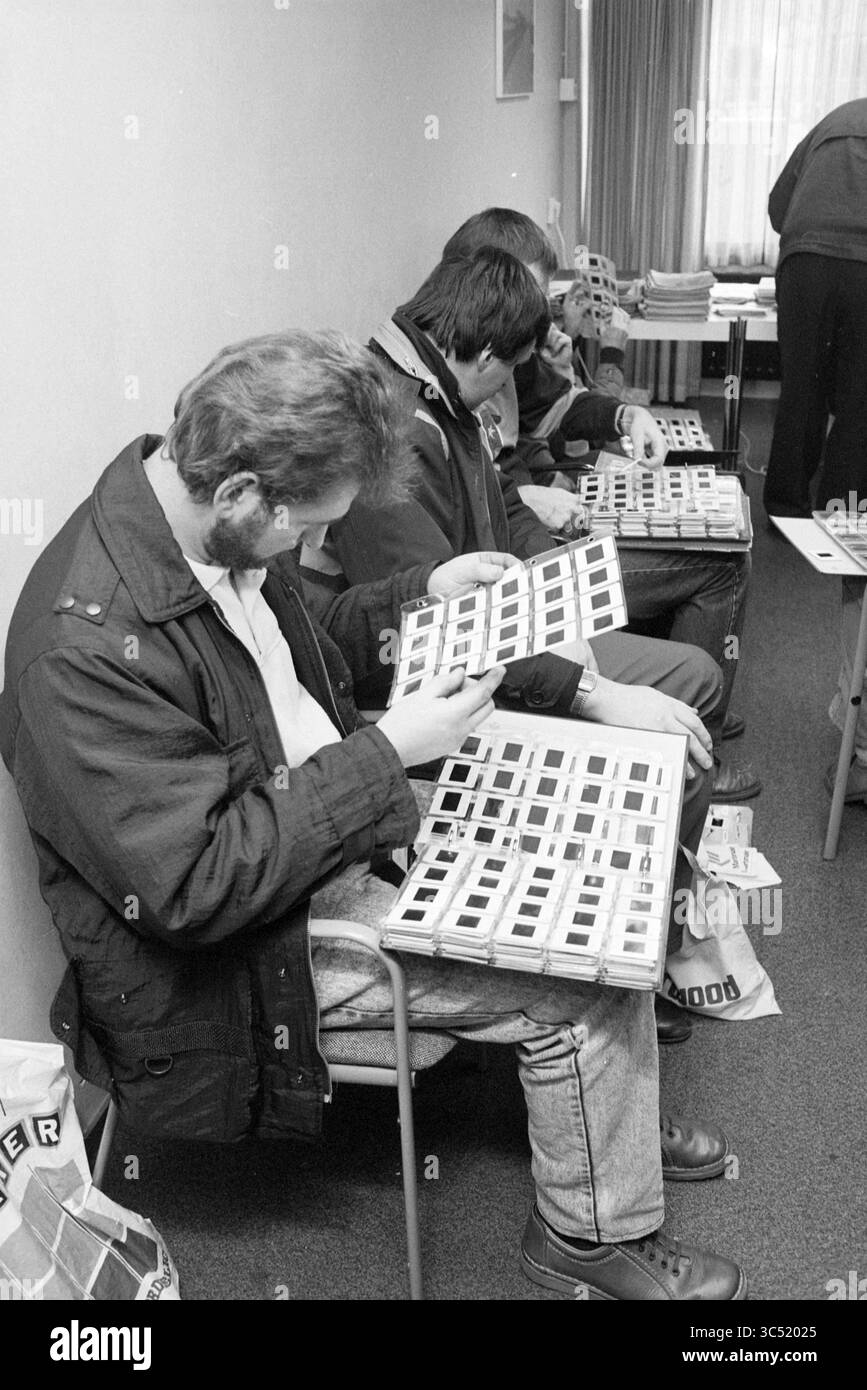 "Riunione degli "spotters" degli aerei, H'dorp", aerei, Hoofddorp, Paesi Bassi, 06-01-1990 Whizgle News, Dutch Desk, Paesi Bassi, 1950-2000 Un gruppo di persone esamina le diapositive esposte in una serie di vassoi organizzati, seduti comodamente in una sala modesta progettata per la visualizzazione e la discussione. L'atmosfera suggerisce un incontro incentrato sulla condivisione e l'apprezzamento di storie visive, con l'attenzione fissata sulle diapositive nelle loro mani. Foto Stock