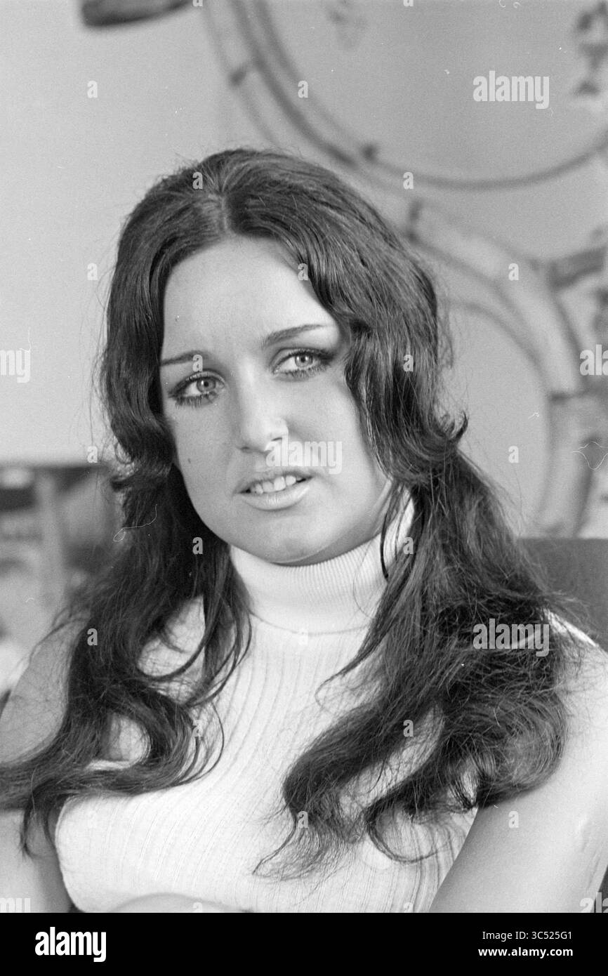 Ritratto di una donna, 00-08-1968 Whizgle News, Dutch Desk, Paesi Bassi, 1950-2000 Una donna con i capelli lunghi e scuri e gli occhi azzurri si siede con cura, indossando un maglione dal collo alto. La sua espressione trasmette un mix di serietà e introspezione, mentre lo sfondo suggerisce uno spazio accogliente e vissuto. Foto Stock