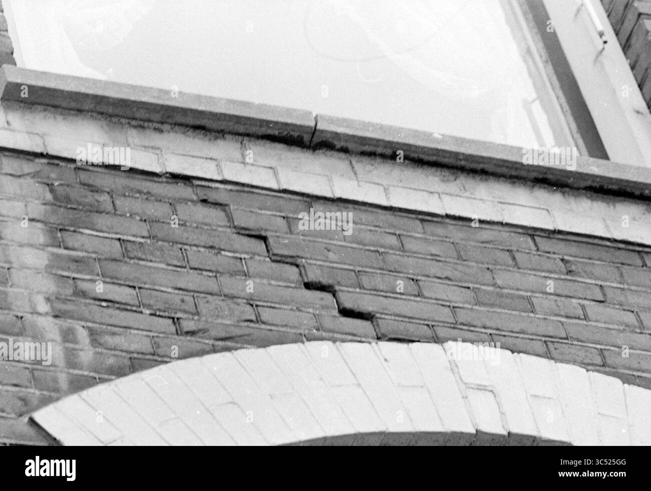 Crepe sulla facciata dell'angolo Nieuwe Gracht di Kinderhuisvest, Haarlem, Nieuwe Gracht, Nederland Whizgle News, Dutch Desk, paesi Bassi, 1950-2000 Una vista ravvicinata di un muro di mattoni che mostra incrinature evidenti, evidenziando l'usura e l'invecchiamento della struttura. Sopra, una sporgenza si estende con parte di una finestra visibile sullo sfondo. Foto Stock