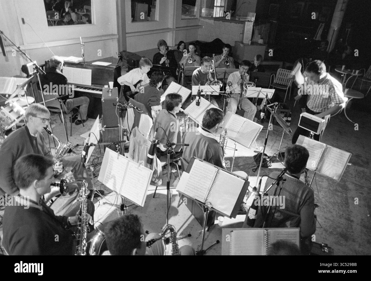 Radio in diretta nella fattoria Hoofddorp, radio, Hoofddorp, Paesi Bassi, 26-02-1989 Whizgle News, Dutch Desk, Paesi Bassi, 1950-2000 Si esibisce Un vivace ensemble jazz, con musicisti posizionati in un semicerchio, impegnati nella loro musica. Un direttore li conduce dal davanti, mentre gli spartiti musicali riposano su un supporto di fronte a ogni giocatore, catturando l'energia creativa della prova. Foto Stock