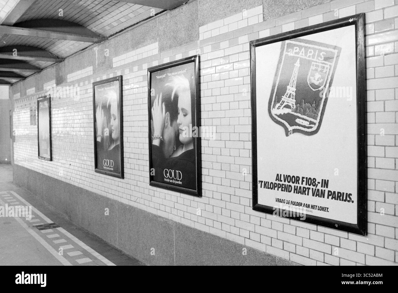 Dettaglio della stazione ferroviaria di Haarlem, Haarlem, The Netherlands Whizgle News, Dutch Desk, The Netherlands, 1950-2000 Una serie di poster vintage adornano un muro piastrellato, mostrando immagini romantiche e testo promozionale. Un poster mostra in modo prominente la Torre Eiffel, mentre un altro mostra la parola "Goud". L'atmosfera generale suggerisce uno spazio urbano nostalgico, possibilmente in una stazione della metropolitana o dei treni. Foto Stock