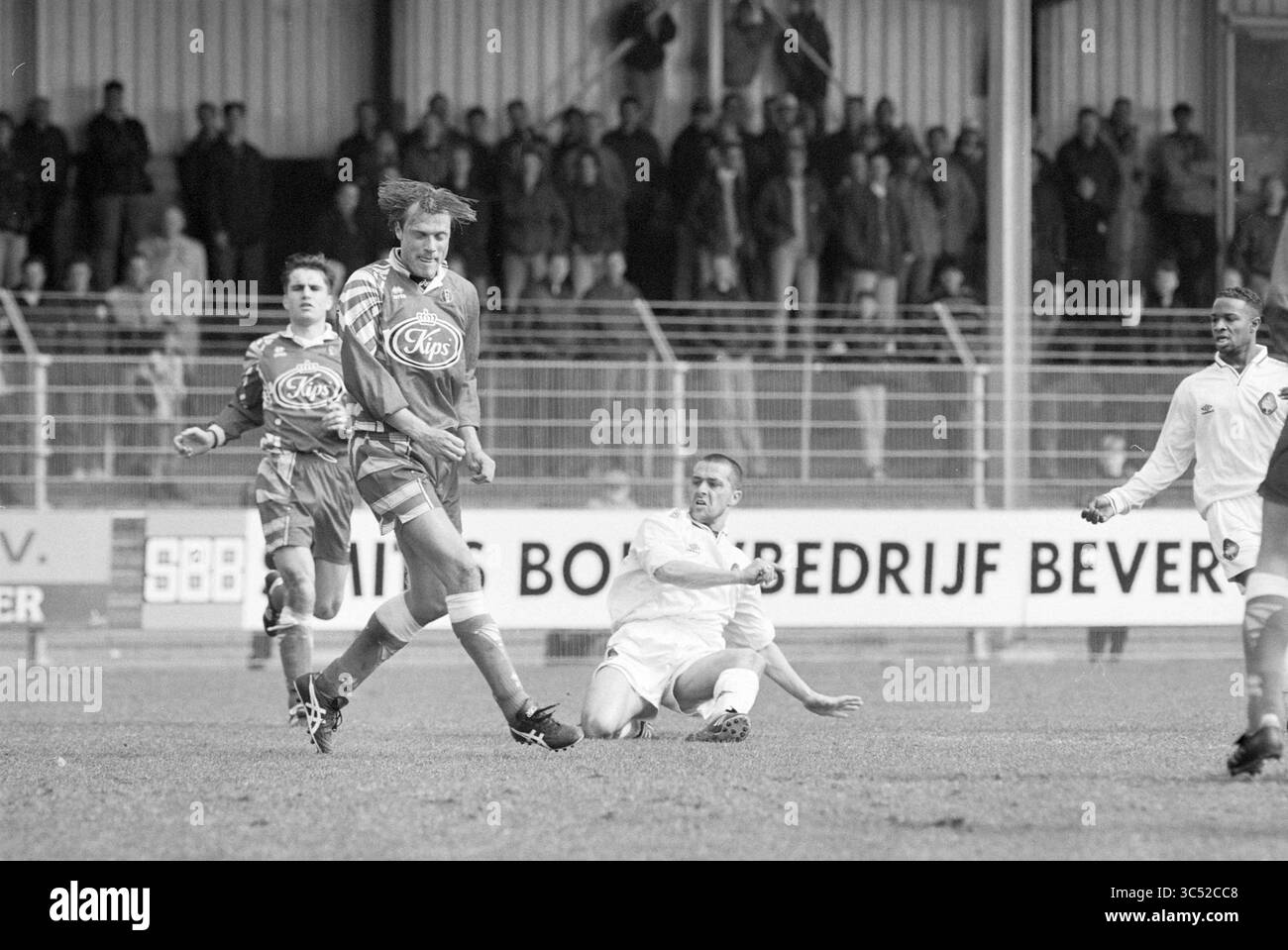 Partita di calcio Telstar - Helmond sprt, Velsen, 08-04-1996 Whizgle News, Dutch Desk, Paesi Bassi, 1950-2000 Una partita di calcio in azione, in cui un giocatore manovra abilmente la palla mentre un avversario tenta di affrontarlo da terra. Gli spettatori possono essere visti in sottofondo, osservando l'intensa commedia. Foto Stock