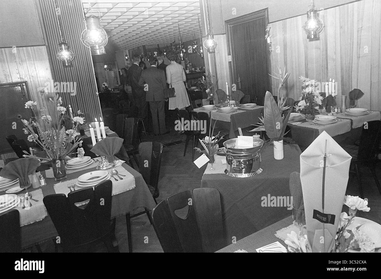 Apertura del ristorante di pesce, apertura, apertura, messa in servizio, 14-04-1973 Whizgle News, Dutch Desk, Paesi Bassi, 1950-2000 Un accogliente spazio da pranzo adornato con tavoli ordinati con centrotavola floreale ed eleganti stoviglie, allestito per una riunione. L'illuminazione soffusa delle lampade a sospensione crea un'atmosfera invitante, mentre un piccolo gruppo di persone conversano sullo sfondo, aggiungendo un'atmosfera di un evento sociale. Foto Stock Apertura del ristorante di pesce, apertura, apertura, messa in servizio, 14-04-1973 Whizgle News, Dutch Desk, Paesi Bassi, 1950-2000 Un accogliente spazio da pranzo adornato con tavoli ordinati con centrotavola floreale ed eleganti stoviglie, allestito per una riunione. L'illuminazione soffusa delle lampade a sospensione crea un'atmosfera invitante, mentre un piccolo gruppo di persone conversano sullo sfondo, aggiungendo un'atmosfera di un evento sociale. Foto Stock