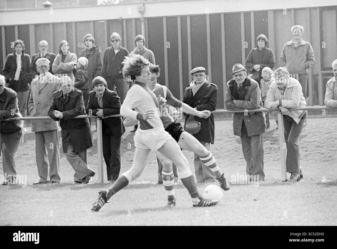 Football SV Dio, 00-04-1980 Whizgle News, Dutch Desk, Paesi Bassi, 1950-2000 Un momento emozionante sul campo in cui due giocatori gareggiano per la palla, mentre una folla accattivante guarda da dietro le quinte, mostrando una serie di reazioni, dall'eccitazione alla concentrazione. Foto Stock