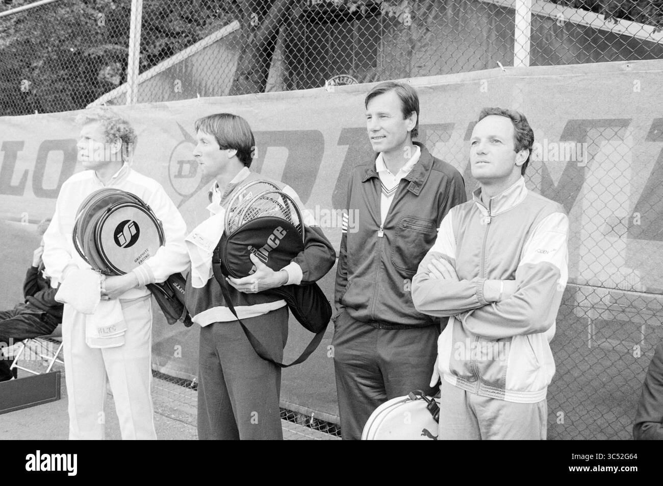 Partita di tennis Tom Okker Whizgle News, Dutch Desk, Paesi Bassi, 1950-2000 Un gruppo di quattro uomini si trova fianco a fianco, ognuno con borse da tennis e indossa un abbigliamento sportivo. Le loro espressioni riflettono la concentrazione e l'anticipazione mentre osservano la scena davanti, possibilmente preparandosi per una partita o un evento. Dietro di loro, una recinzione e uno striscione in un luogo sportivo. Foto Stock