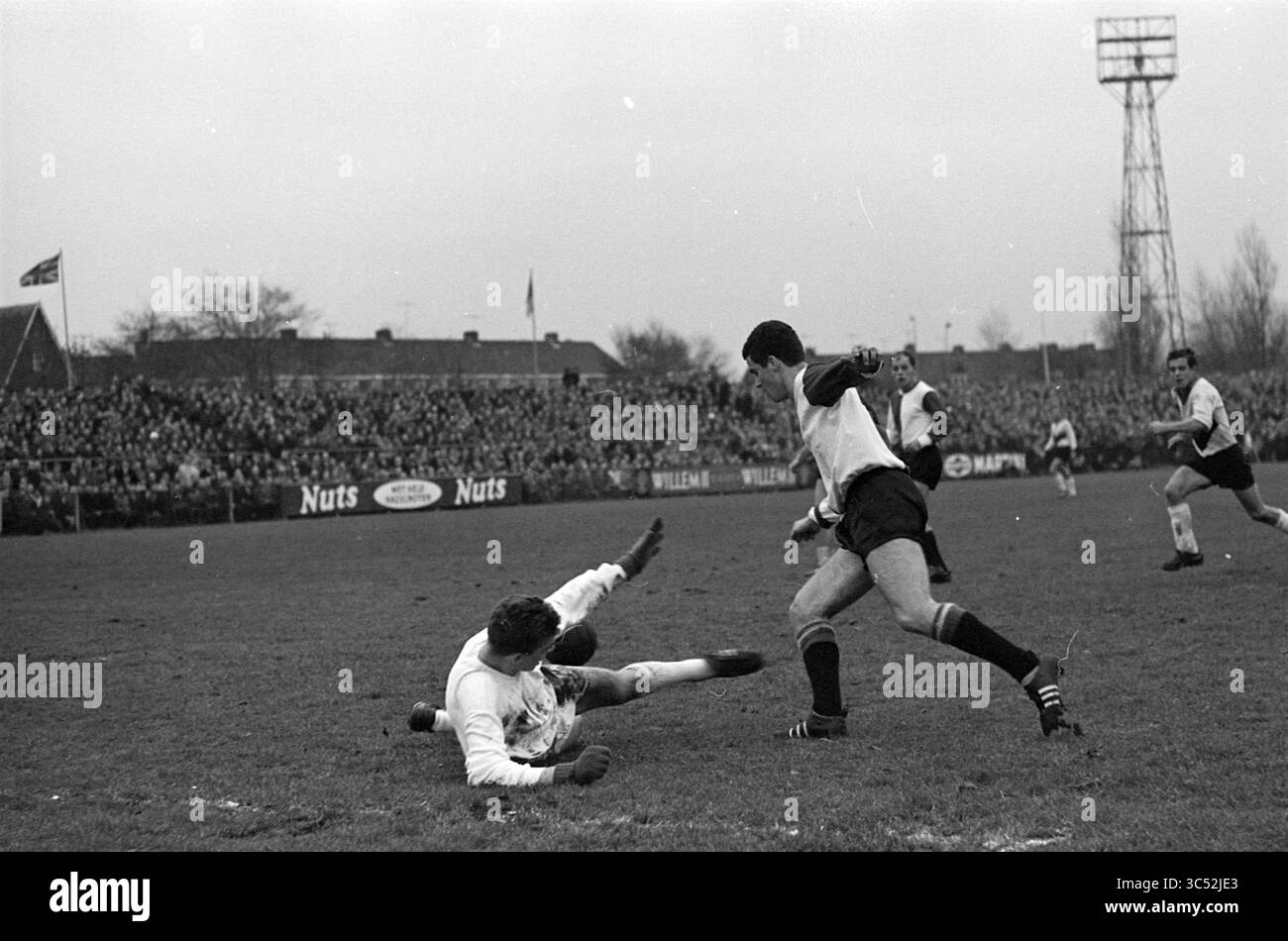 EDO - Feyenoord (coppa), calcio, 17-11-1963 Whizgle News, Dutch Desk, Paesi Bassi, 1950-2000 Una partita di calcio si svolge su un campo erboso, con giocatori impegnati in un gioco dinamico. Un giocatore si tuffa per intercettare la palla mentre un altro riesce a superare abilmente la palla, guidando l'intensa competizione di fronte a una folla numerosa. Foto Stock