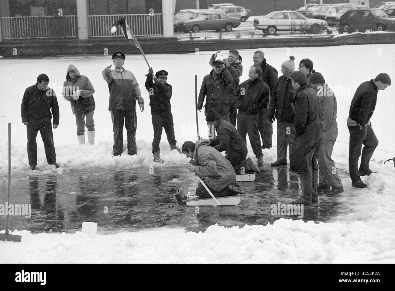 Prikslee Harbour master Spaarne, 14-02-1991 Whizgle News, Dutch Desk, Paesi Bassi, 1950-2000 Un gruppo di individui si riunisce all'aperto in un ambiente innevato, impegnandosi in varie attività. Alcuni stanno ripulendo la neve mentre altri osservano, e una persona sembra dirigere gli sforzi. La scena cattura un senso di comunità e di lavoro di squadra in condizioni di vento. Foto Stock
