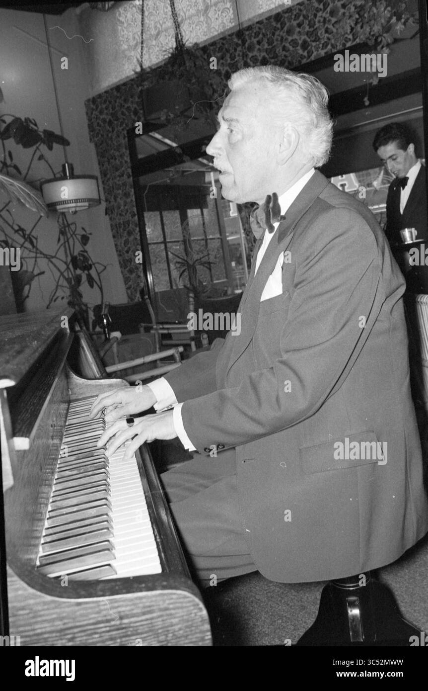 Pianista al Queenie bar Zandvoort, Persons Singing and Music, Zandvoort, 05-04-1979 Whizgle News, Dutch Desk, Paesi Bassi, 1950-2000 Un uomo distinto in un smoking suona il pianoforte con intensità concentrata, circondato da un interno elegante che suggerisce un incontro elegante. Sullo sfondo, un cameriere assiste delicatamente gli ospiti, aggiungendo un'atmosfera raffinata. Foto Stock