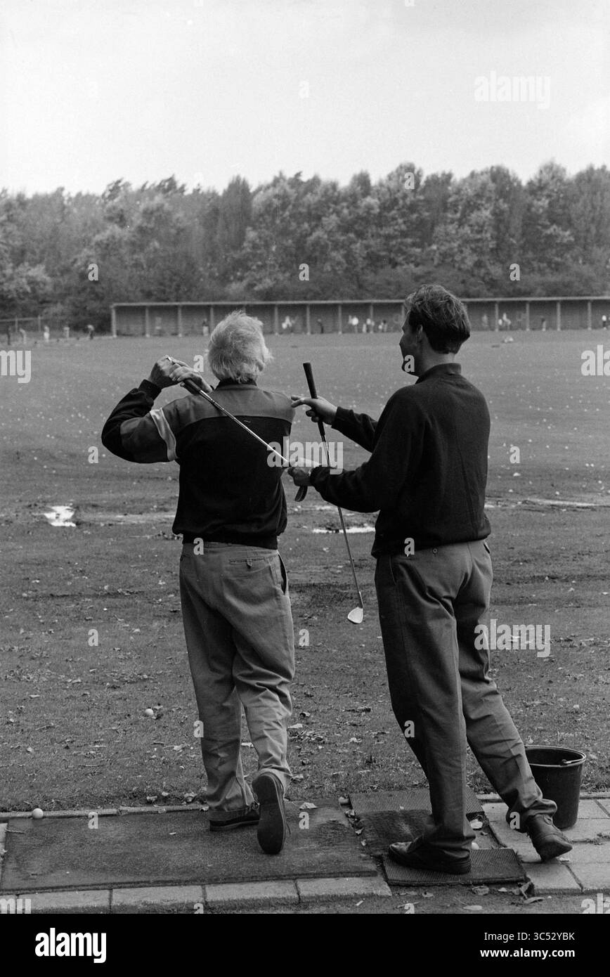 Corsi di golf, Verum fa., Spaarnwoude, Spaarnwoude, 05-09-1995 Whizgle News, Dutch Desk, Paesi Bassi, 1950-2000 due persone su un campo pratica da golf, con una persona che mostra una tecnica di swing mentre l'altra osserva da vicino. La scena cattura l'atmosfera di pratica e istruzione in mezzo a uno sfondo di alberi. Foto Stock