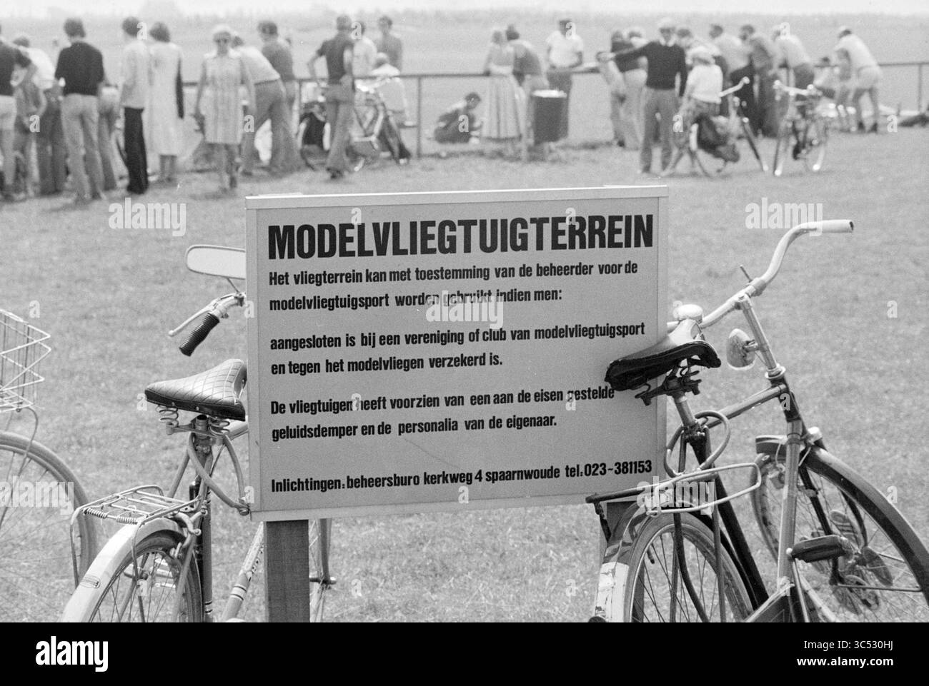Report Spaarnwoude Bos, Spaarnwoude, 22-08-1978 Whizgle News, Dutch Desk, Paesi Bassi, 1950-2000 Un cartello indicante un modello di area di volo di un velivolo, con regole e linee guida per gli utenti. In primo piano, due biciclette sono parcheggiate nelle vicinanze, mentre una folla di persone può essere vista impegnati in varie attività sullo sfondo. Foto Stock
