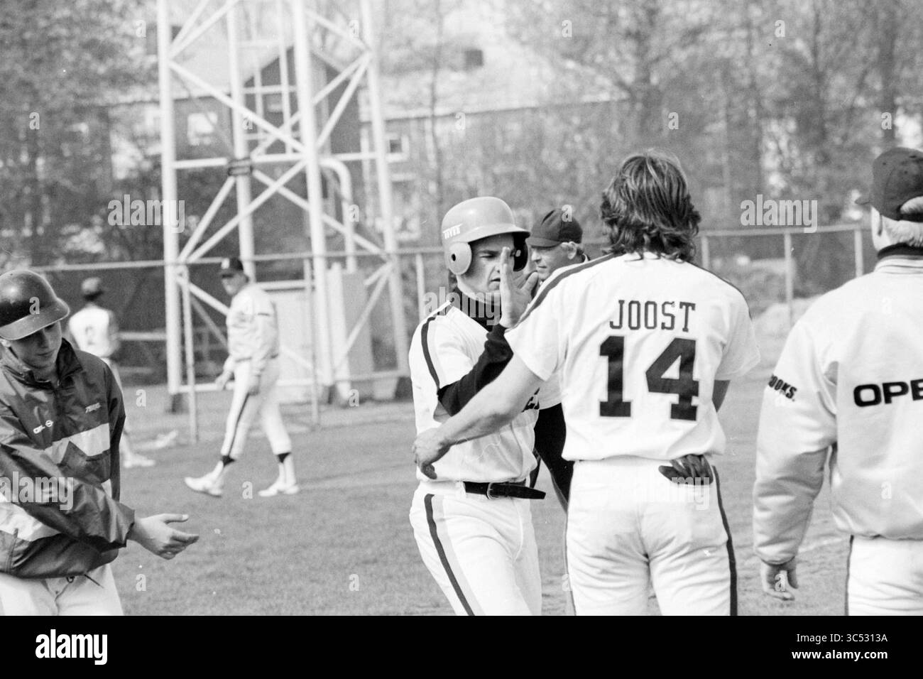 Nicols - Sparta, Baseball Haarlem Nicols, 17-04-1988 Whizgle News, Dutch Desk, Paesi Bassi, 1950-2000 Un gruppo di giocatori di baseball si impegna in un momento vivace sul campo, celebrando un gioco di successo. Un giocatore che indossa un casco condivide un gesto di congratulazioni con un altro, che porta il numero 14 sulla sua maglia. L'atmosfera è vivace, indicativa del lavoro di squadra e del cameratismo nel gioco. Foto Stock