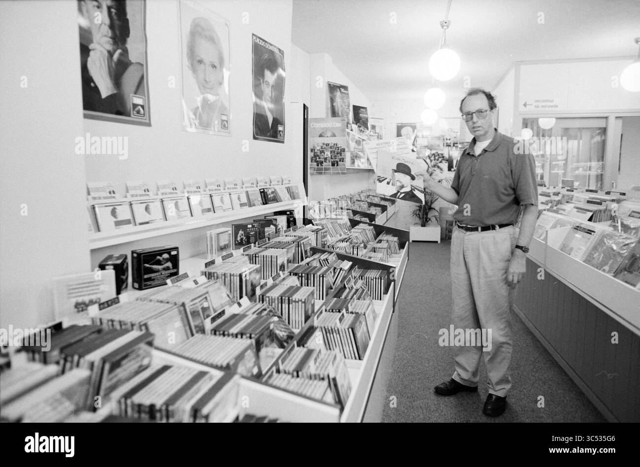 Klassica Z. Records and disc case, Haarlem, Paesi Bassi, 07-09-1988 Whizgle News, Dutch Desk, i Paesi Bassi, 1950-2000 Un uomo si trova in un negozio di musica, circondato da scaffali pieni di CD e dischi. I manifesti di artisti famosi appendono alle pareti mentre tiene un disco, esaminandolo con cura in mezzo a una vivace collezione di musica. Foto Stock