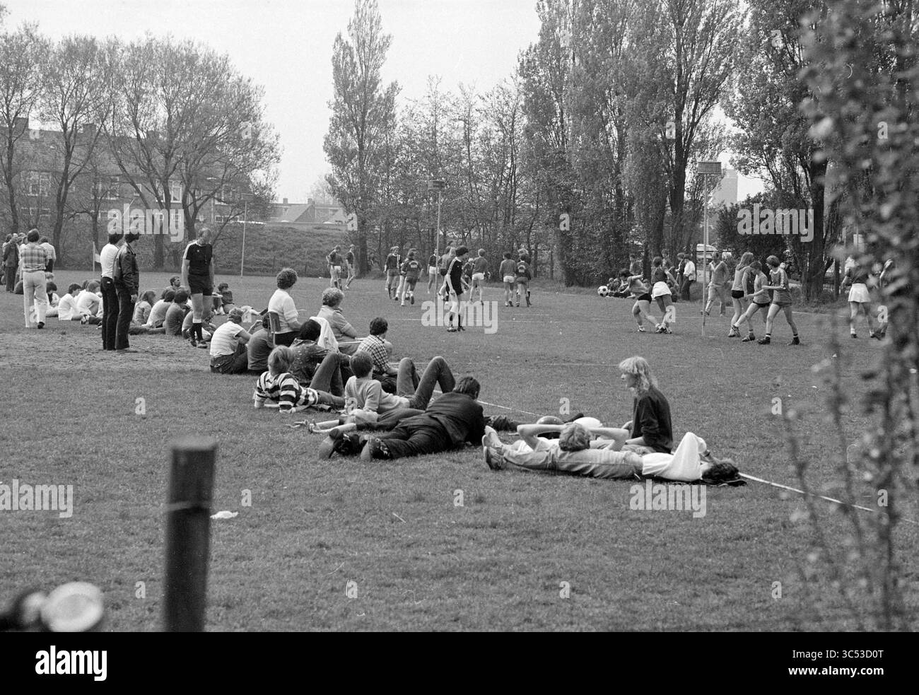 School korfball Beverwijk, Korfball, Schools, Beverwijk, Paesi Bassi, 09-05-1981 Whizgle News, Dutch Desk, Paesi Bassi, 1950-2000 Una vivace scena in un parco dove gruppi di persone stanno godendo di varie attività. Alcune si rilassano sull'erba, chiacchierano o si rilassano, mentre altre praticano sport amichevoli nelle vicinanze, creando una vibrante atmosfera di svago e comunità. Gli alberi allineano lo sfondo, aggiungendo un'impostazione naturale. Foto Stock