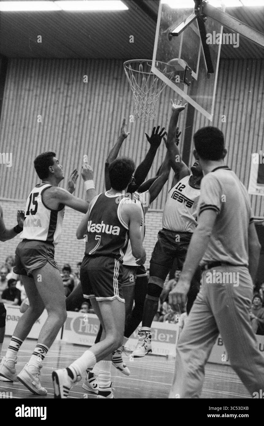 Basket, 00-00-1988 Whizgle News, Dutch Desk, Paesi Bassi, 1950-2000 Un giocatore di basket salta verso il canestro, tentando un colpo drammatico in mezzo a una partita tesa, mentre i difensori si allungano per bloccare lo sforzo. I compagni di squadra e gli avversari sono catturati in un momento di azione, tutti concentrati sul gioco che si svolge. Foto Stock