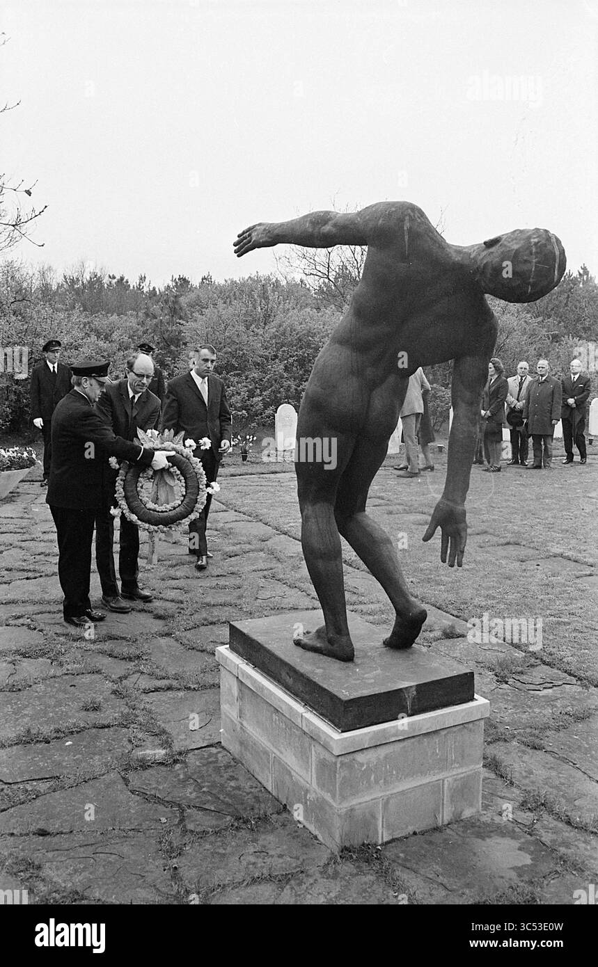 Wreath laying Duinhof IJmuiden, commemorazioni, 04-05-1972 Whizgle News, Dutch Desk, Paesi Bassi, 1950-2000 Un gruppo di individui si trova solennemente vicino a una statua impressionante di una figura distorta, il suo braccio si allungava come se si avvicinasse. Una persona sta mettendo una corona alla sua base, mentre altri osservano silenziosamente sullo sfondo, suggerendo un momento di memoria e riflessione. Foto Stock