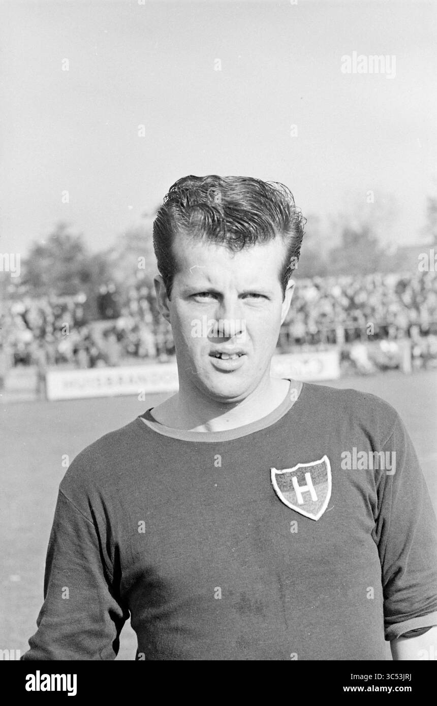 Ritratto del giocatore FC Haarlem Whizgle News, Dutch Desk, Paesi Bassi, 1950-2000 Un giovane giocatore di calcio si erge in sicurezza sul campo, indossando una maglia girocollo con uno scudo. Dietro di lui, una folla di tifosi entusiasti aggiunge l'atmosfera di un giorno di partita vivace. Foto Stock