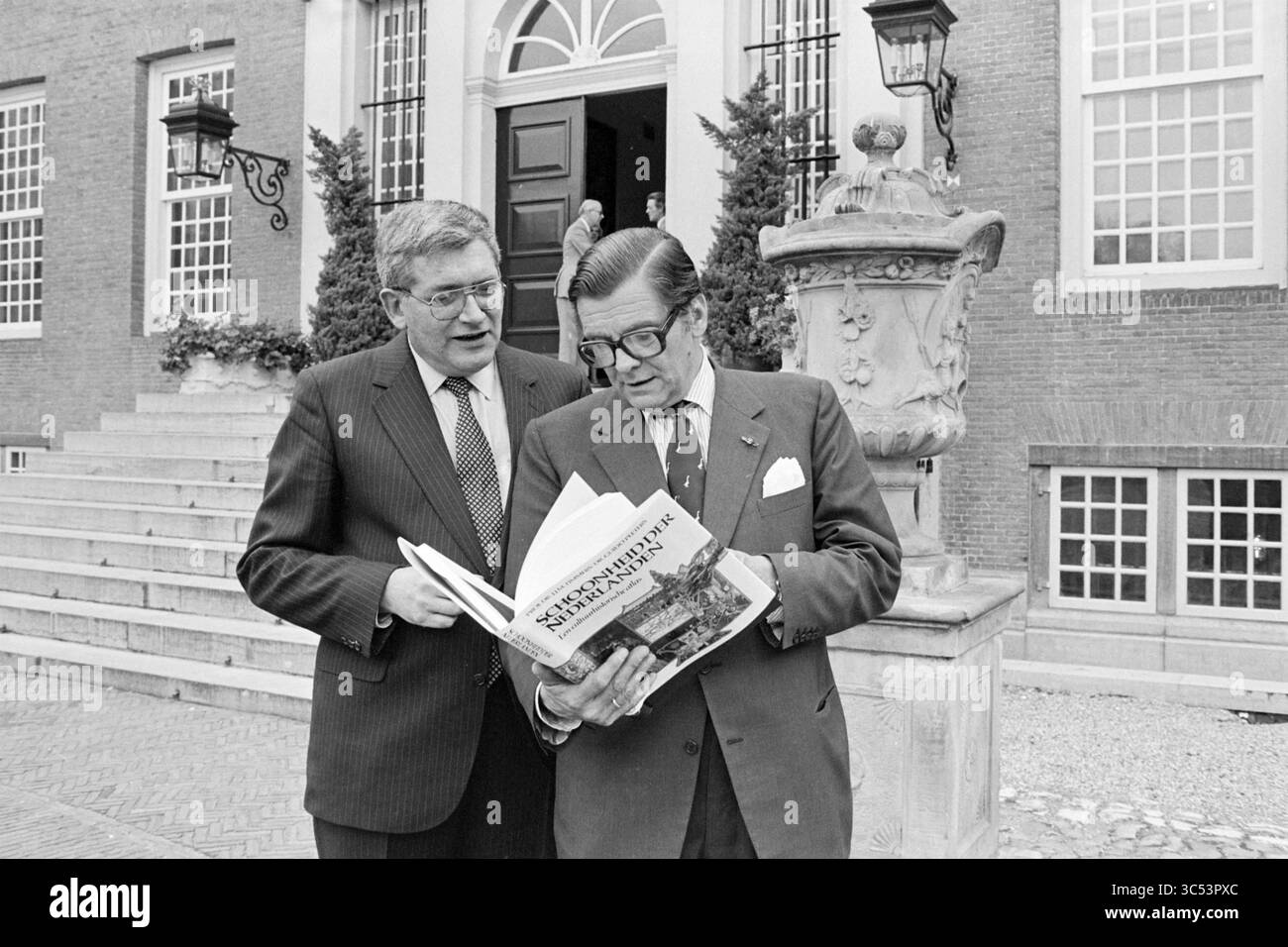 Libro di presentazione Beauty of the Netherlands (Elsevier), 19-09-1980 Whizgle News, Dutch Desk, The Netherlands, 1950-2000 due uomini stanno fuori da un elegante edificio, impegnati in discussione come uno tiene un libro aperto. Sembra che stiano esaminando da vicino i suoi contenuti, circondati da verde e architettura classica. Foto Stock Libro di presentazione Beauty of the Netherlands (Elsevier), 19-09-1980 Whizgle News, Dutch Desk, The Netherlands, 1950-2000 due uomini stanno fuori da un elegante edificio, impegnati in discussione come uno tiene un libro aperto. Sembra che stiano esaminando da vicino i suoi contenuti, circondati da verde e architettura classica. Foto Stock