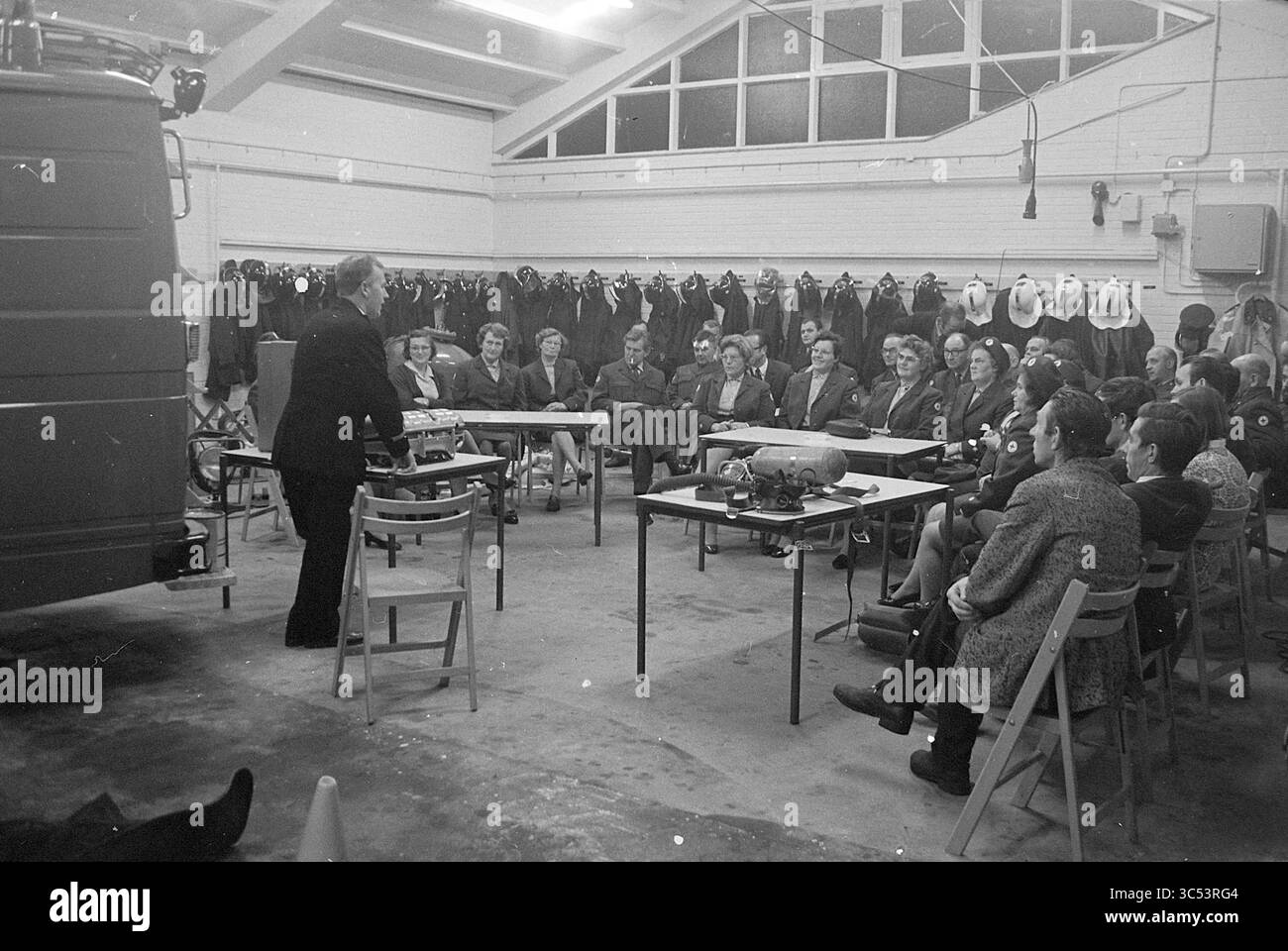 Croce Rossa ai vigili del fuoco di Heemskerk, vigili del fuoco, Croce Rossa, ospedale della Croce Rossa, 17-09-1970 Whizgle News, Dutch Desk, Paesi Bassi, 1950-2000 Un oratore si rivolge a un pubblico attento seduto intorno ai tavoli in una sala spaziosa, piena di attrezzatura da immersione e attrezzature appese alle pareti. I partecipanti, vestiti in vari stili, sembrano impegnati mentre ascoltano la presentazione. Foto Stock