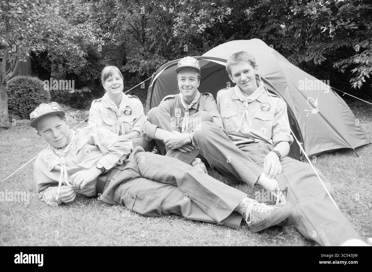 Four members scouting, Santpoort, Santpoort, 06-09-1991 Whizgle News, Dutch Desk, i Paesi Bassi, 1950-2000 Un gruppo di quattro scout si rilassa all'esterno di una tenda da campeggio, vestita con uniformi e cappelli. Si siedono casualmente, sorridono e si godono la compagnia reciproca in un ambiente naturale. Foto Stock