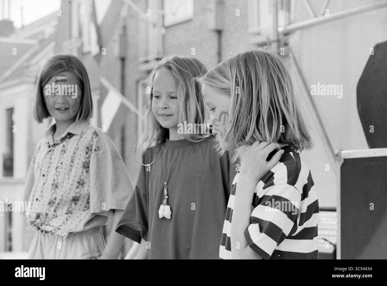 Play Back, BL'daal, Bloemendaal, 29-04-1993 Whizgle News, Dutch Desk, i Paesi Bassi, 1950-2000 tre bambini stanno insieme, impegnati in un momento di cameratismo. Una ragazza indossa una camicia a righe, un'altra sfoggia una maglia a motivi geometrici e la terza è decorata con vernice per il viso. Le loro espressioni trasmettono un senso di curiosità e di connessione mentre si concentrano su qualcosa di fronte a loro. Foto Stock