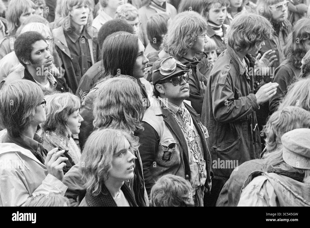 Pop festival Sports Park, Music, Report, 16-09-1972 Whizgle News, Dutch Desk, i Paesi Bassi, 1950-2000 Una folla diversificata di persone si è impegnata intensamente in un evento, mostrando un mix di acconciature e moda dell'epoca. Alcuni sono vestiti con abbigliamento casual, mentre altri sono dotati di accessori esclusivi, che riflettono la vibrante cultura del tempo. Le espressioni spaziano dall'eccitazione alla contemplazione, catturando un momento di esperienza collettiva. Foto Stock