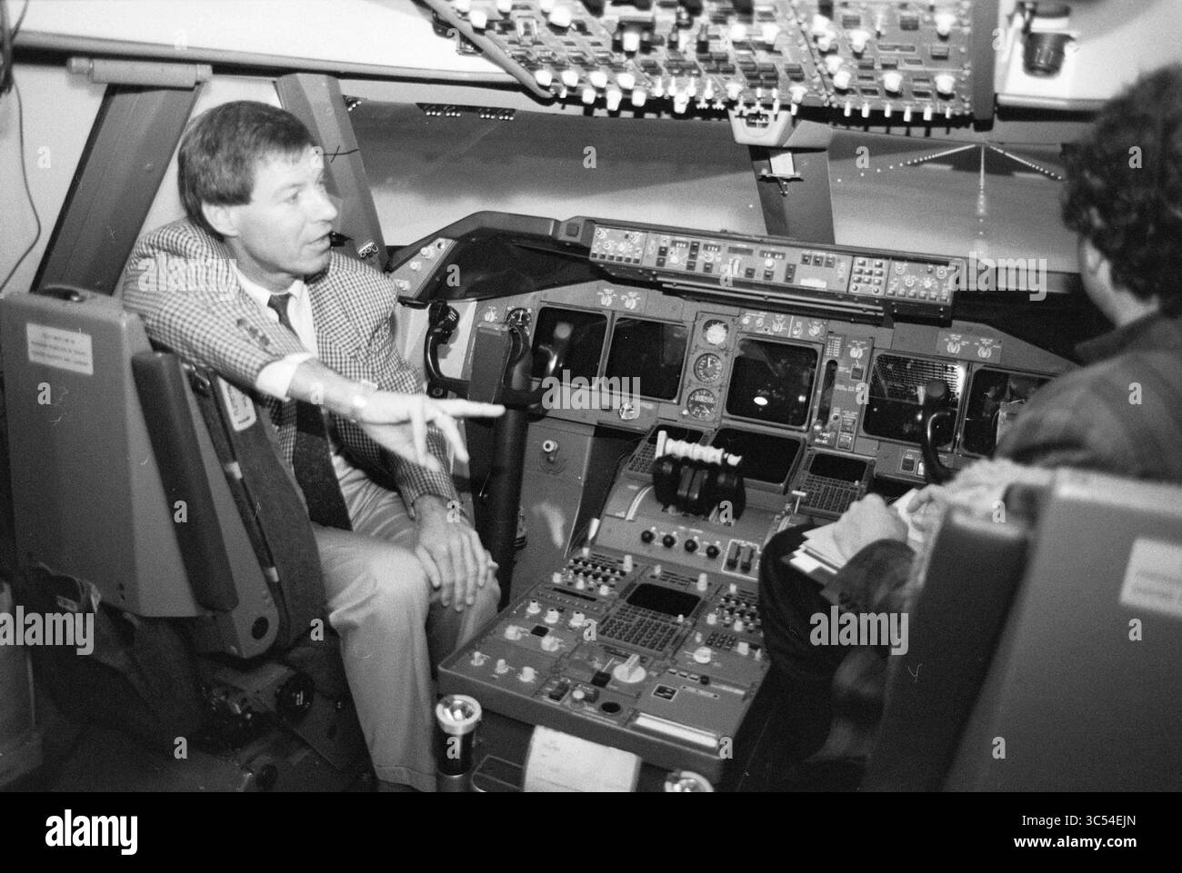 Simulatore di volo 747-400, Schiphol, Schiphol, 28-01-1992 Whizgle News, Dutch Desk, i Paesi Bassi, 1950-2000 due persone sono sedute in una cabina di pilotaggio, con un gesto animato mentre discutono di controlli e strumenti. La cabina di pilotaggio è piena di varie leve, pulsanti e display, sottolineando l'ambiente tecnico dell'aviazione. Foto Stock