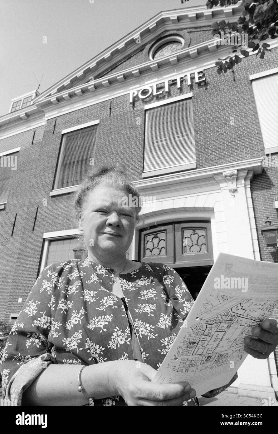 Lia Blesgraaf, 21-07-1994 Whizgle News, Dutch Desk, Paesi Bassi, 1950-2000 Una donna si trova di fronte ad un edificio in mattoni con la parola "POLITIE" ben visibile sopra l'ingresso, tenendo una mappa in mano e guardando direttamente lo spettatore, vestito con una parte superiore a motivi floreali. Foto Stock