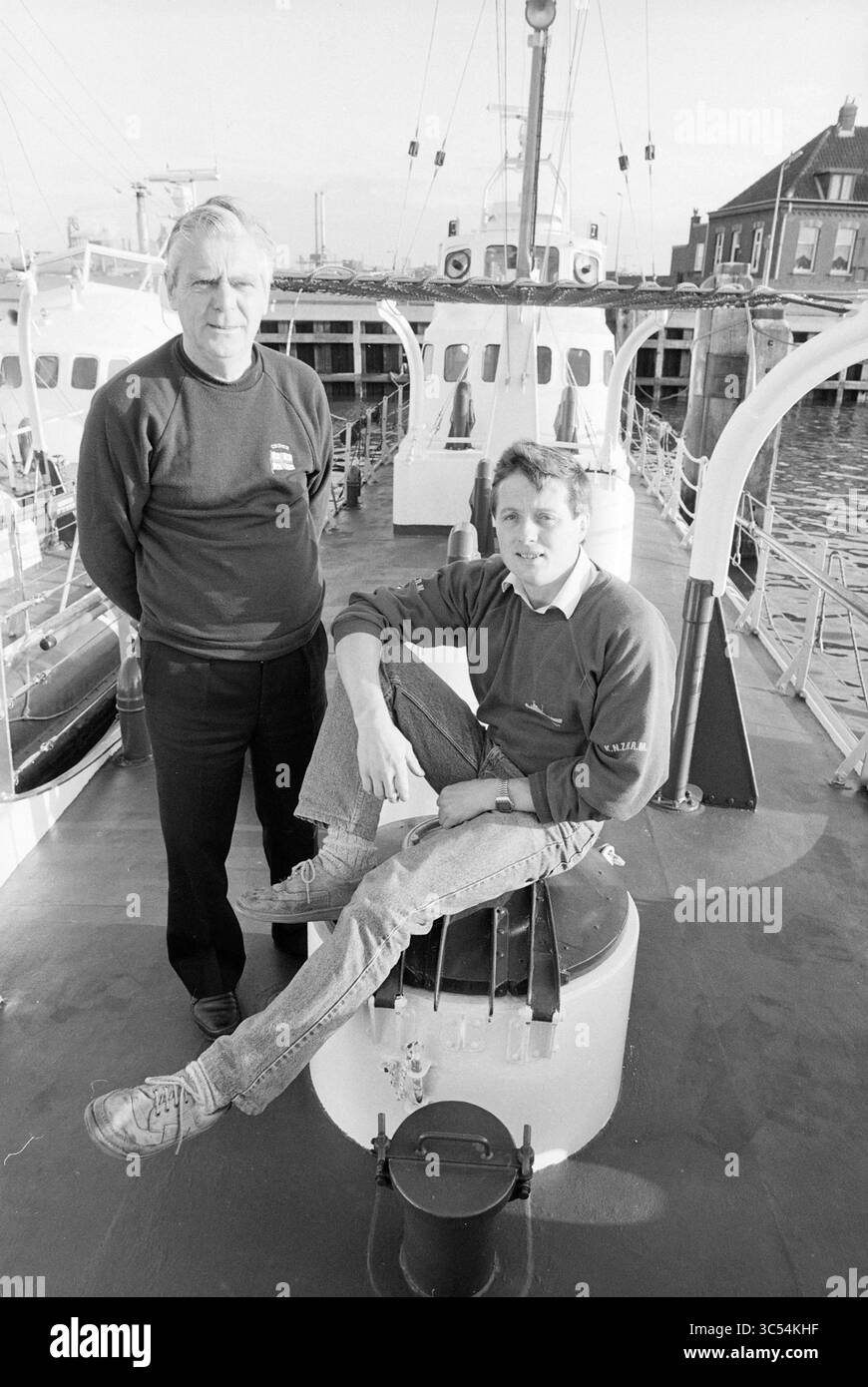 2 signori al battello di soccorso IJmuiden, soccorso, brigata di soccorso, servizio di soccorso, IJmuiden, i Paesi Bassi, 31-10-1988 Whizgle News, Dutch Desk, Paesi Bassi, 1950-2000 due uomini si trovano a bordo di una nave, uno casualmente arroccato su una struttura circolare mentre l'altro si trova con sicurezza nelle vicinanze. Condividono un momento sul ponte, con il porto sullo sfondo e le barche visibili in lontananza. L'ambientazione trasuda un senso di cameratismo e vita marittima. Foto Stock 2 signori al battello di soccorso IJmuiden, soccorso, brigata di soccorso, servizio di soccorso, IJmuiden, i Paesi Bassi, 31-10-1988 Whizgle News, Dutch Desk, Paesi Bassi, 1950-2000 due uomini si trovano a bordo di una nave, uno casualmente arroccato su una struttura circolare mentre l'altro si trova con sicurezza nelle vicinanze. Condividono un momento sul ponte, con il porto sullo sfondo e le barche visibili in lontananza. L'ambientazione trasuda un senso di cameratismo e vita marittima. Foto Stock