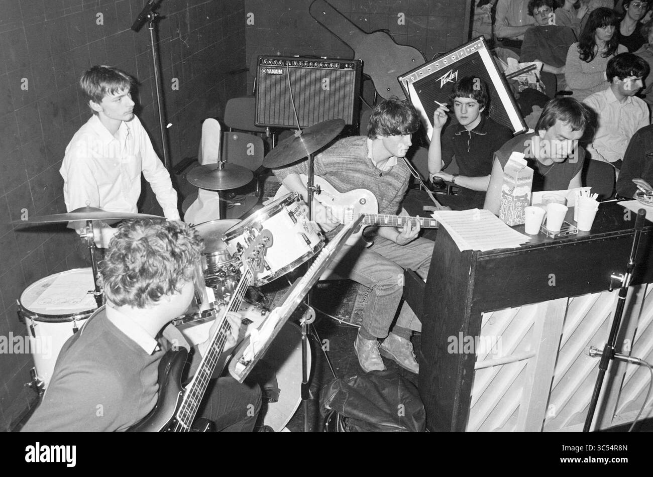 Prove tre stuiver opera in Egelantier, Opera, operetta, 26-03-1983 Whizgle News, Dutch Desk, i Paesi Bassi, 1950-2000 Un vivace gruppo di musicisti si esibisce sul palco, circondato da strumenti come batteria e chitarre. L'ambiente è pieno di un pubblico attento, creando un'atmosfera vibrante mentre i musicisti si concentrano sui loro strumenti e spartiti musicali. Foto Stock