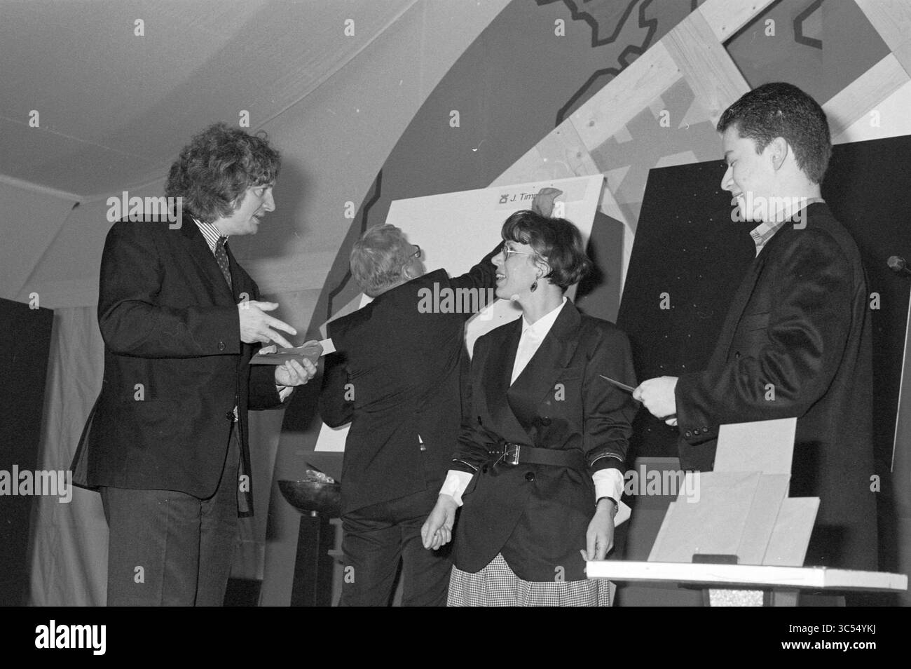 56th Hoogovens Chess Tournament dal 14 al 30 gennaio 1994, Wijk aan Zee, 00-01-1994 Whizgle News, Dutch Desk, Paesi Bassi, 1950-2000 Un gruppo di quattro persone si impegna in una performance interattiva sul palco, con due uomini che gestiscono animatamente e una donna che sorride mentre partecipa. L'atmosfera e' vivace mentre collaborano a un compito creativo, mostrando un mix di entusiasmo e cameratismo. Foto Stock