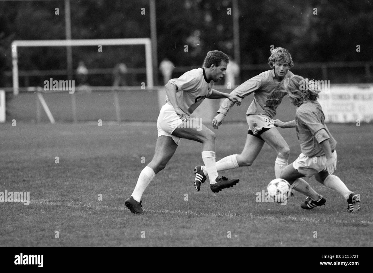 Football @@ - Fulmars, 21-08-1990 Whizgle News, Dutch Desk, Paesi Bassi, 1950-2000 tre giocatori di calcio sono attivamente impegnati in una partita, con uno che dribbling la palla mentre gli altri inseguono da vicino. La tensione e il movimento mettono in risalto il lavoro di squadra e lo spirito competitivo sul campo. Foto Stock