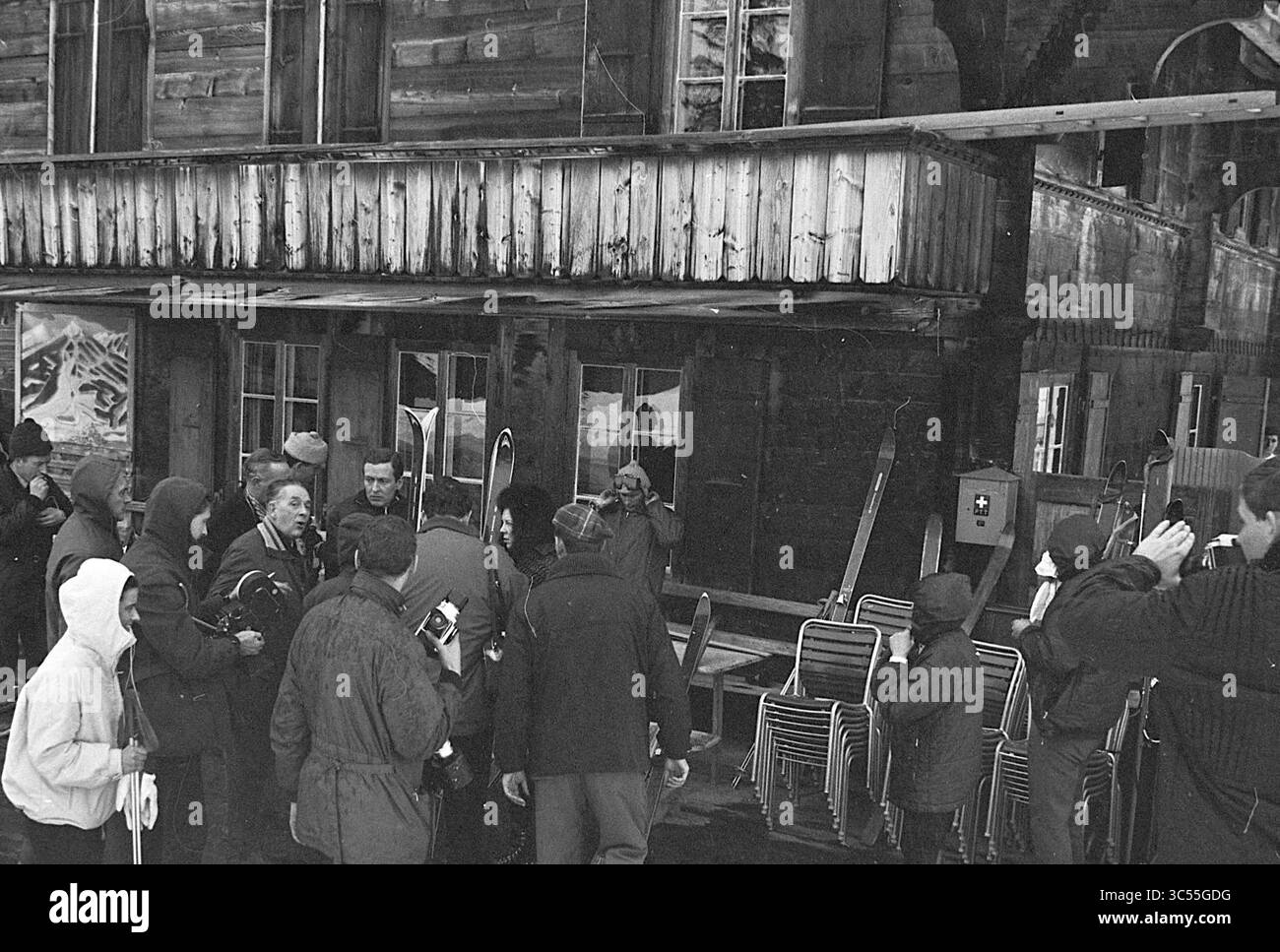Potrebbe. Famiglia in vacanza (Gstaad), Kon. Visite e ricevimenti, persone, funerali, 22-01-1966 Whizgle News, Dutch Desk, i Paesi Bassi, 1950-2000 Una scena affollata fuori da un edificio rustico, dove un gruppo di persone, alcune in abbigliamento invernale, si riuniscono in giro mentre altre sembrano impegnarsi in conversazione o scattare foto. La struttura dietro di loro presenta una facciata in legno resistente agli agenti atmosferici, che suggerisce un'attività all'aperto probabilmente legata allo sci o agli sport invernali. Foto Stock