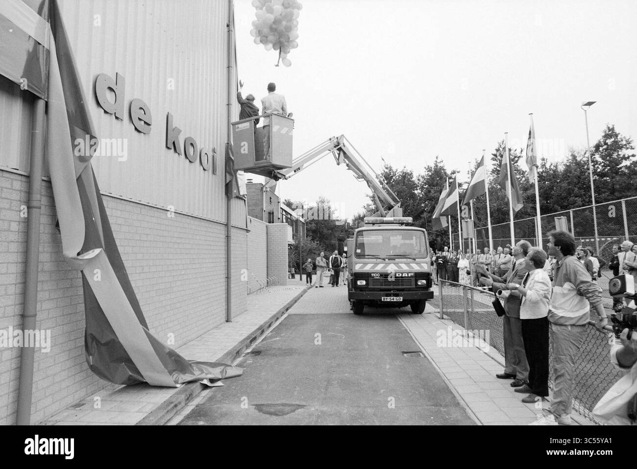 Apertura del negozio sportivo Bennebroek, apertura, apertura, settimana dello sport, Bennebroek, 25-08-1989 Whizgle News, Dutch Desk, Paesi Bassi, 1950-2000 Una grande folla si raduna mentre un veicolo dotato di ascensore sale per rilasciare palloncini colorati, mentre gli spettatori attendono con impazienza la presentazione di una nuova struttura, contrassegnata da un cartello prominente. Nelle vicinanze sono esposte bandiere di varie nazioni, che aggiungono un'atmosfera festosa all'evento. Foto Stock