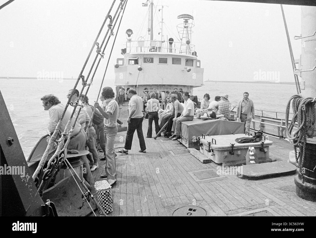 Relazione sulla pesca sportiva nel Mare del Nord, relazione, 19-07-1972 Whizgle News, Dutch Desk, Paesi Bassi, 1950-2000 Un gruppo di persone è riunito sul ponte di una barca, impegnato in conversazioni e varie attività, mentre un'altra nave è attraccata nelle vicinanze. La scena cattura il cameratismo e la vivace atmosfera della vita sull'acqua. Foto Stock